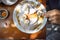 Hands slicing tasty pancakes with powdered sugar and bananas above wooden table