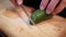 Hands slowly slicing chili pepper on cutting board