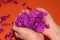 In the hands of small pieces of purple paper. Children`s hands on an orange background. Fun game