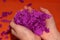 In the hands of small pieces of purple paper. Children`s hands on an orange background. Fun game