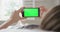 Hands, smartphone and green screen in bedroom, mockup space or social media app for marketing. Closeup, phone and person