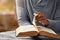 Hands, spiritual and a man reading the bible at a table outdoor in the park for faith or belief in god. Book, story and