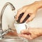 Hands with sponge wash the cup under running water in kitchen