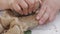 hands with stone to grind grain seeds into powder in a mortar