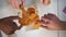 Hands taking nuggets from paper box on table. Top view. Unrecognizable people simultaneously spreading arms to get