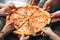 Hands taking pizza slices from wooden table, close up view.