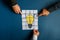 Hands of three businessmen assembling a lightbulb drawn on post it papers
