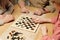 Hands of three senior friendly people gathered by table with checkers