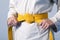 Hands tightening yellow belt on a teenage dressed