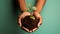 Hands together holding small plant in fertile soil on green background