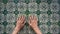 hands touching wall with green azulejo tiles