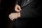 Hands of tuxedo wearing groom fixes cufflink.