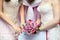 Hands of two brides wearing dresses hold bouquet