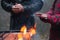 Hands of two people getting warm from a fire outdoors.