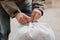 Hands tying white bag in yard