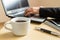 Hands typing on a laptop. Cup of coffee, smartphone and laptop on the desk