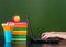 Hands typing on notebook near empty green chalkboard