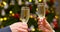 Hands of unknown people clink champagne glasses toast against Christmas tree