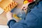 Hands of unrecognizable man in blue long-sleeve shirt beating eggs in blue plastic bowl with wire whisk on table.