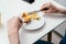 Hands of unrecognizable man cutting with table knife and eating omelette with vegetables with fork on white round plate.