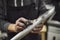 Hands of an unrecognizable person sanding a bicycle frame at his workshop