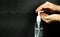 Hands using bottle of hand sanitizer, hand disinfectant on dark background. Woman preventing coronavirus infection during epidemi