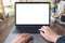 Hands using and typing on laptop with blank white desktop screen and coffee cups on wooden table