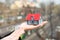 Hands wearing protective gloves holding house model outdoors