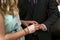 Hands of wedding couple marriage ceremony bride put ring on finger of her lovely groom