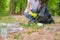 Hands of white shirt woman collect the garbage out from grasses and soil to black bag in the garden with concept save the