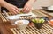 Hands of woman chef rolling up a japanese sushi