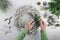 Hands of a woman crafting an advent wreath from pale wood with green fir branches, gray candles and Christmas decoration on a