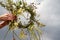 Hands of woman crafting the wreath of wildflowers on a blue cloudy sky