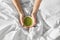 Hands of woman with cup of matcha tea in bed