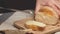 Hands of a woman cutting bread loaf on wooden cutting board