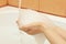 Hands of woman with foam under running water in bathroom