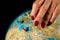 Hands of a woman holding a globe of the planet earth with marked places to travel on vacation