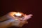 Hands of a woman holding a lit tealight