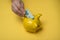 hands of woman insert a twenty euro bank note her yellow piggy bank on yellow background