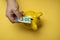 hands of woman insert a twenty euro bank note her yellow piggy bank on yellow background