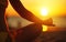 Hands of woman meditating in yoga pose at sunset on beach