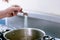 Hands of Woman salting water for cooking.