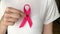 Hands of woman showing breast cancer awareness ribbon. Close-up of a female holding a pink cancer ribbon on World Cancer Day celeb