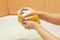 Hands of woman soaping yellow sponge with soap