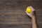 Hands of a woman squeezing a yellow stress ball on the wooden table background