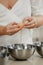 The hands of a woman who is separating the egg white from the yolk above a bowl