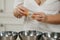 The hands of a woman who is separating the egg white from the yolk above a bowl