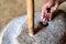 Hands work with millstone to grind sorhum in Sri lankan house