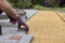 Hands of a worker in gloves laying concrete blocks with a rubber hammer