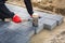 Hands of worker installing concrete paver blocks with rubber hammer